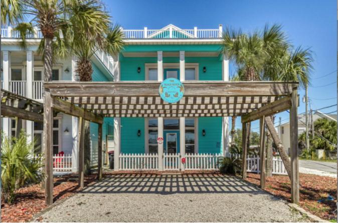 a green house with palm trees in front of it at Deja Blue by Sand Seeker Vacations in Panama City Beach
