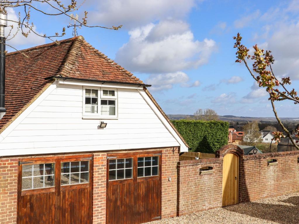 a detached garage with wooden doors and a brick fence at Orchard Retreat in Paddock Wood