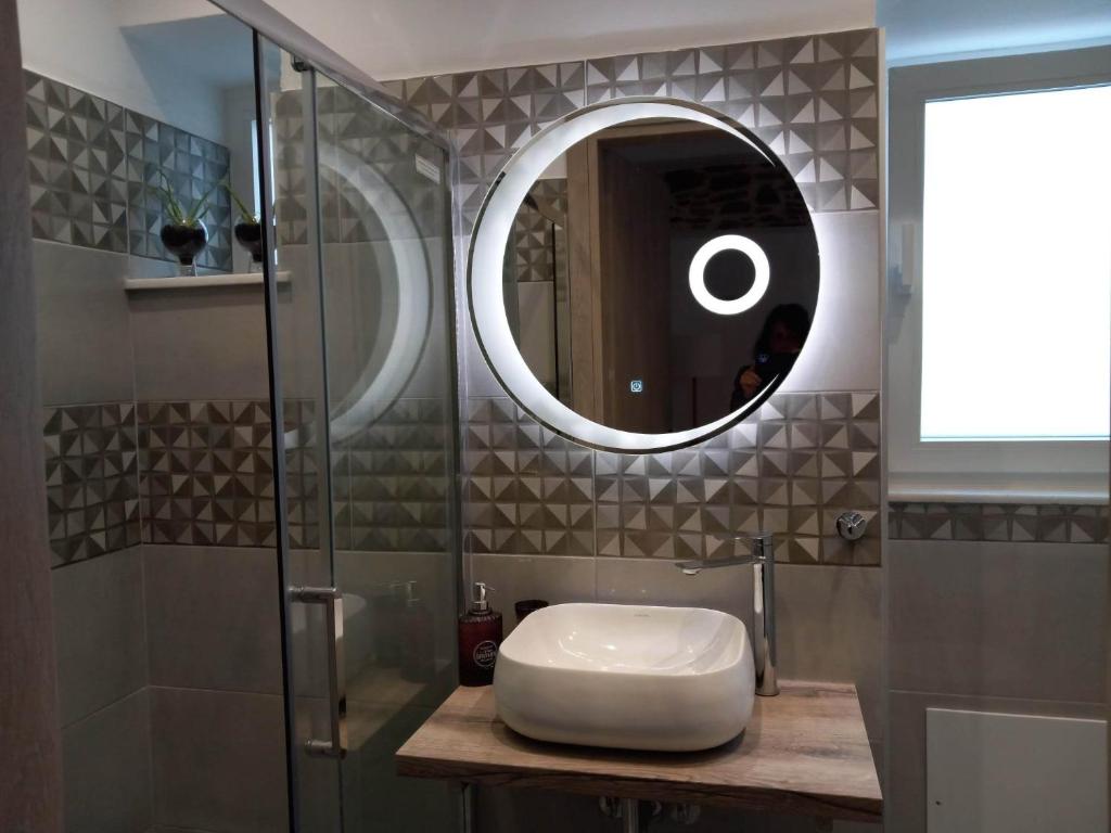 La salle de bains est pourvue d'un lavabo et d'un miroir. dans l'établissement Nisos suite, à Ermoúpoli