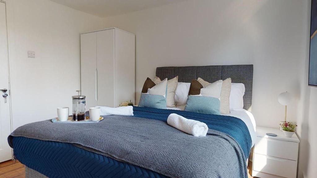 una camera da letto con un grande letto con una coperta blu di Samdel Dulwich Grove 3 Bed Apartment a Londra