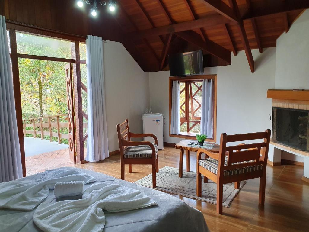um quarto com uma cama, uma mesa e cadeiras em Recanto das Tirivas em Monte Verde