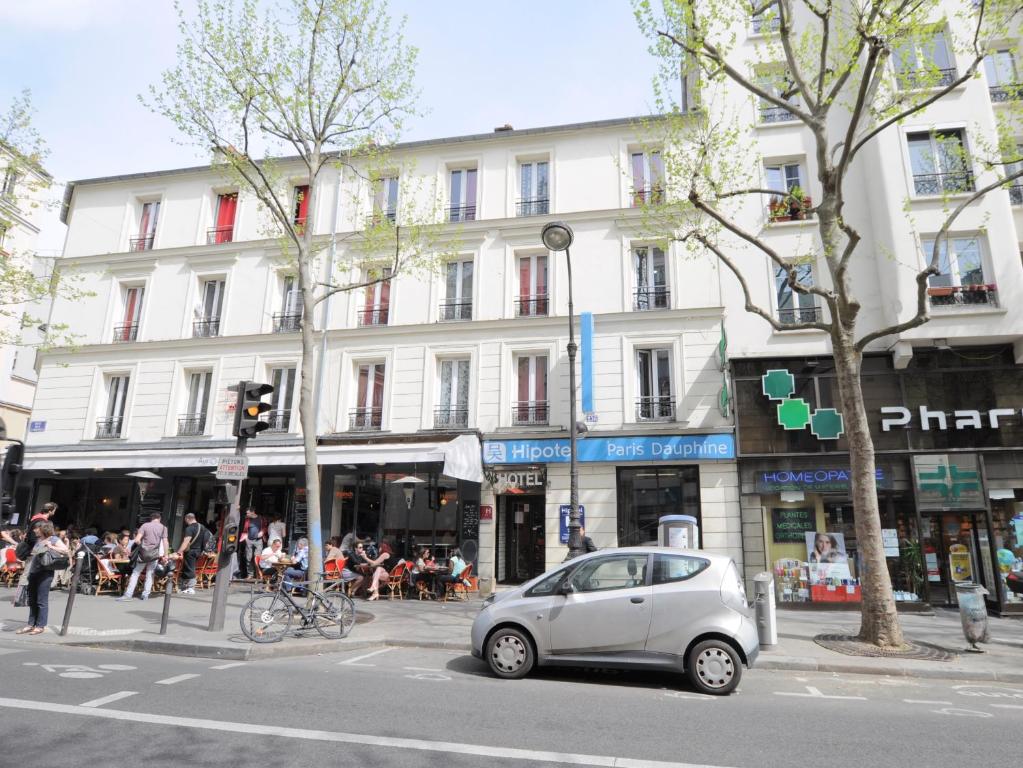 una piccola auto argentata parcheggiata di fronte a un edificio di Hipotel Paris Gambetta République a Parigi