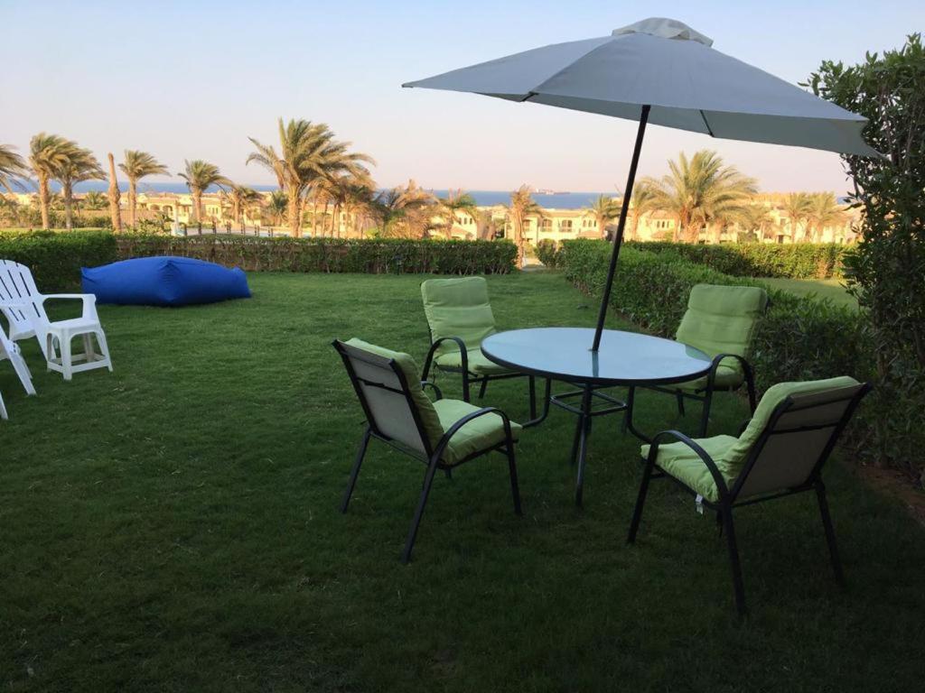 een tafel met stoelen en een parasol in het gras bij La Vista 6 Ain Sokhna Chaleh in Ain Sokhna