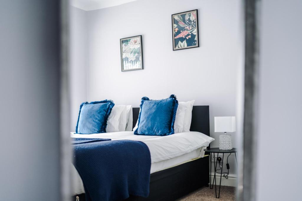 a bedroom with a bed with blue pillows on it at Charming 3-Bedroom Home in Liverpool - FREE Parking in Deysbrook
