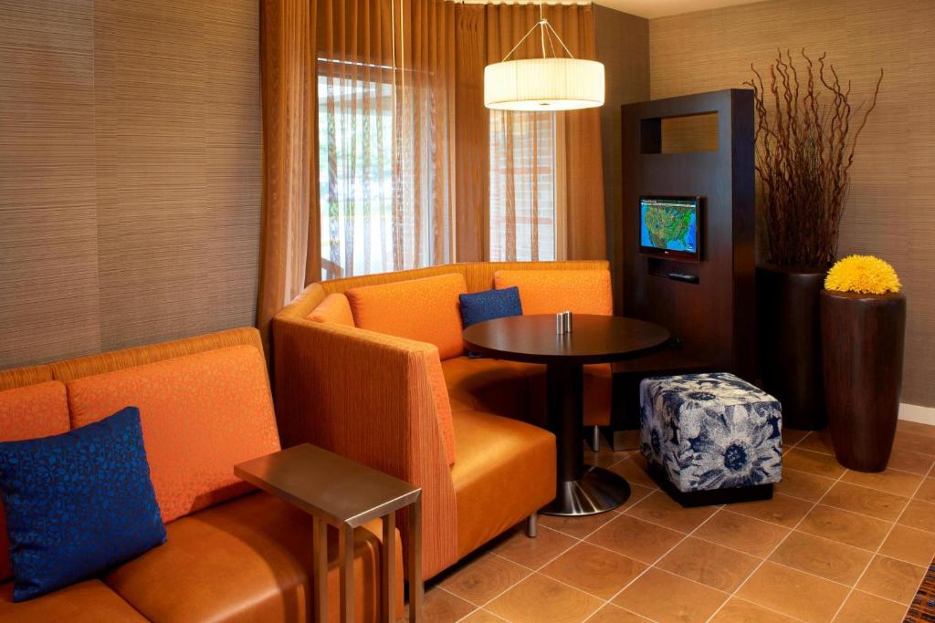 米德堡高地的住宿－克利夫蘭機場南庭院酒店，客厅配有橙色椅子和桌子