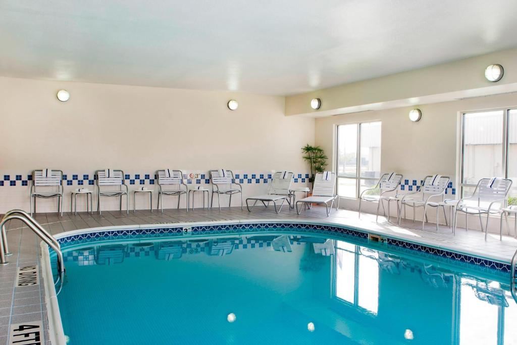 una piscina en una habitación de hotel con sillas y mesas en Fairfield Inn & Suites by Marriott Champaign, en Champaign