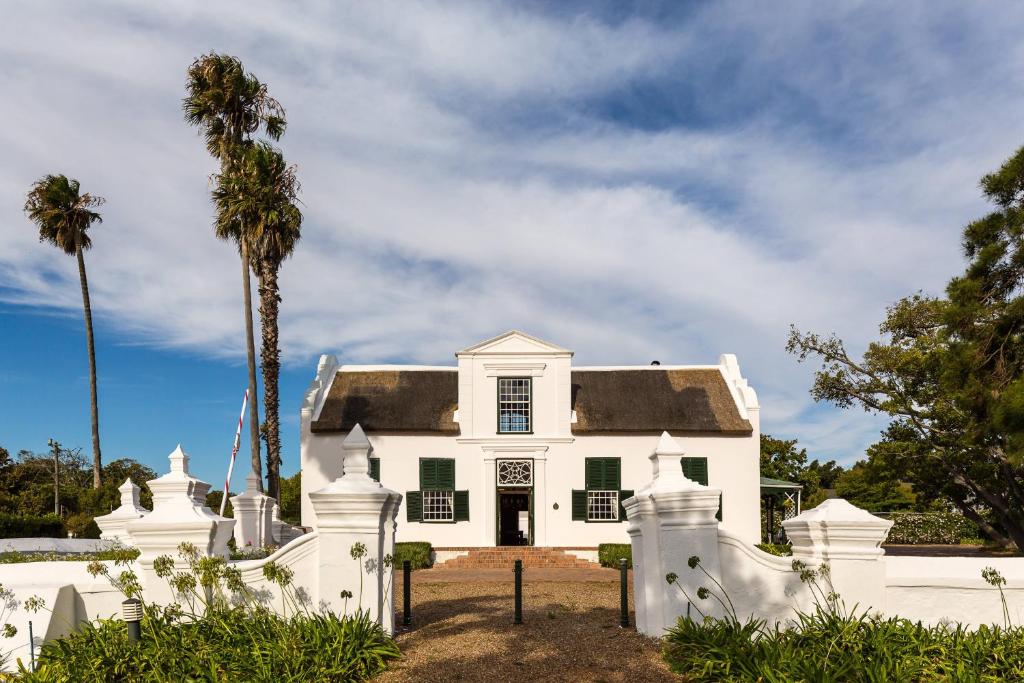 ケープタウンにあるProtea Hotel by Marriott Cape Town Mowbrayのヤシの木が目の前に広がる白い家