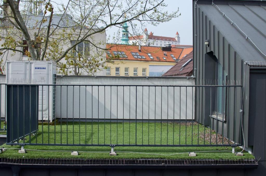 uma cerca com relva ao lado de um edifício em Wild Elephants Hostel em Bratislava