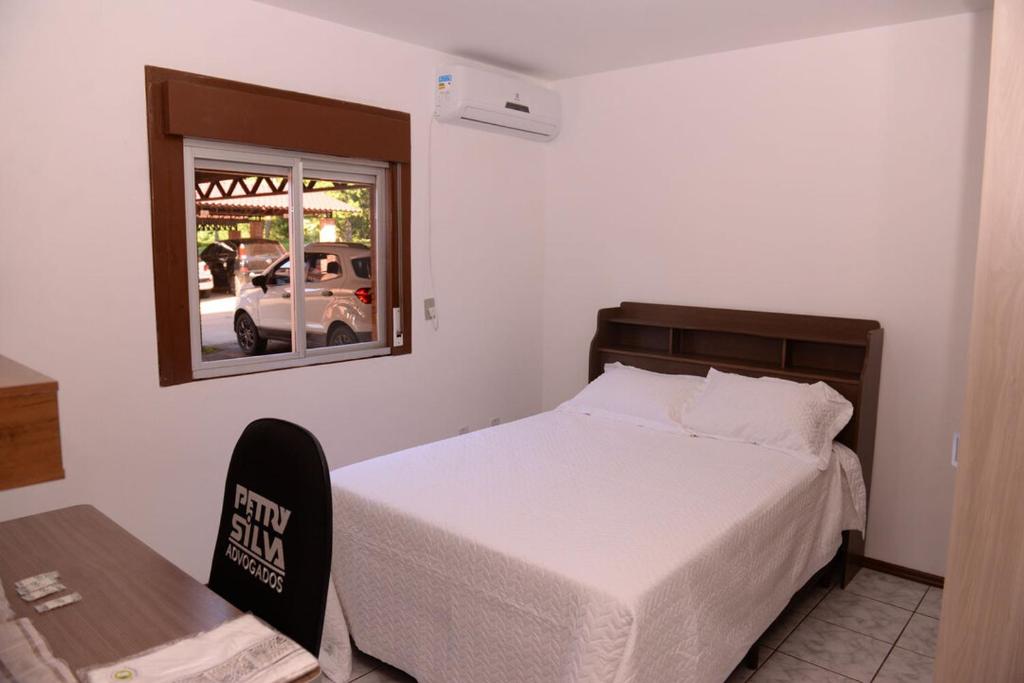 a bedroom with a bed and a chair and a window at Apto completo e aconchegante em Santa Rosa RS in Santa Rosa