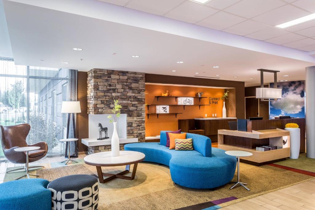 een lobby met een blauwe bank en stoelen en een tafel bij Fairfield Inn & Suites by Marriott Butte in Butte