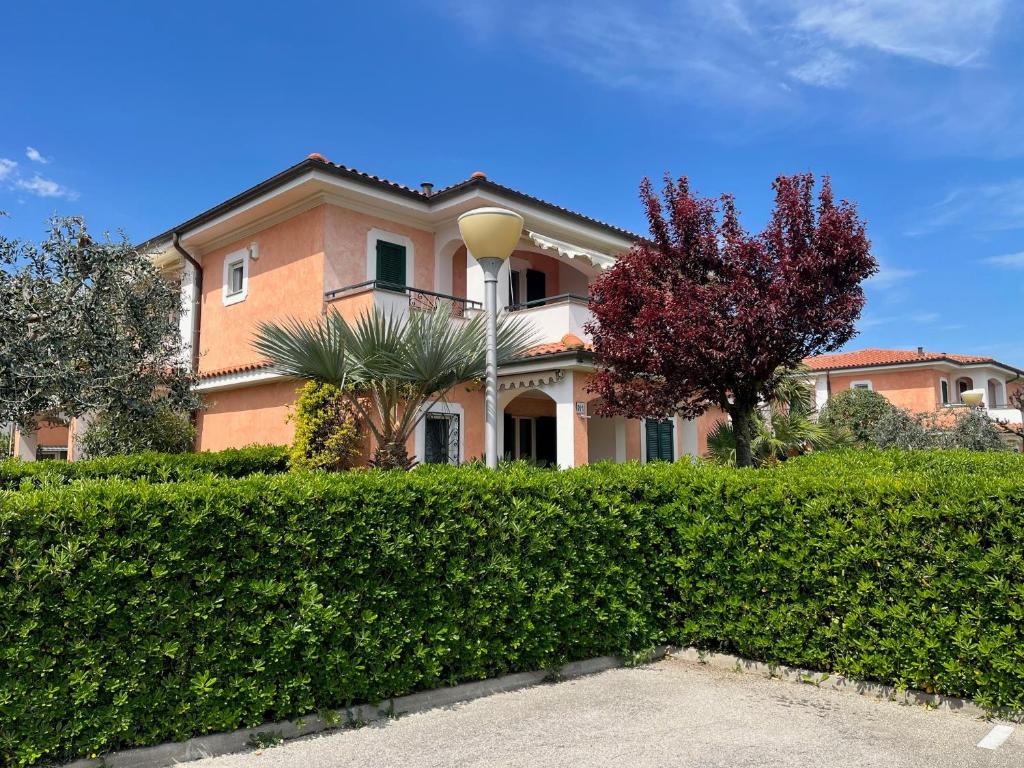 a house with a hedge in front of it at Villa I Giardini del Conero con ombrellone in spiaggia in Porto Recanati
