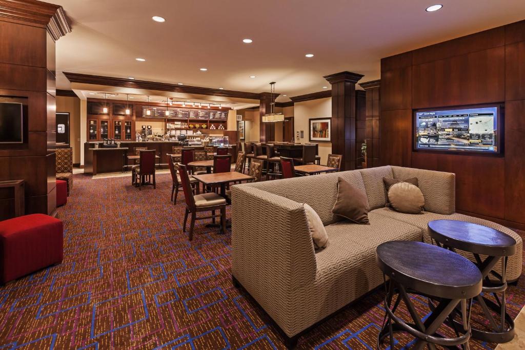 a living room with a couch and tables and a bar at Courtyard by Marriott Odessa in Odessa