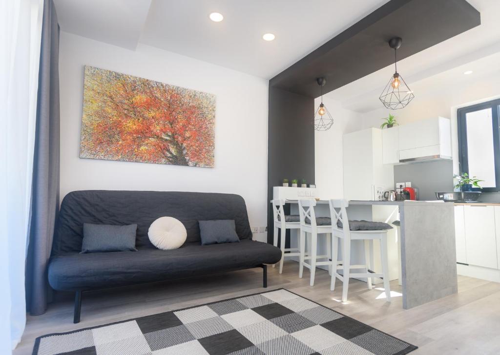 Una sala de estar con un sofá y una cocina. en Sarah's Penthouse in Sliema, en Sliema