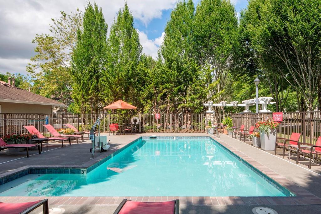 a swimming pool with chairs and a fence at TownePlace Suites by Marriott Portland Hillsboro in Hillsboro