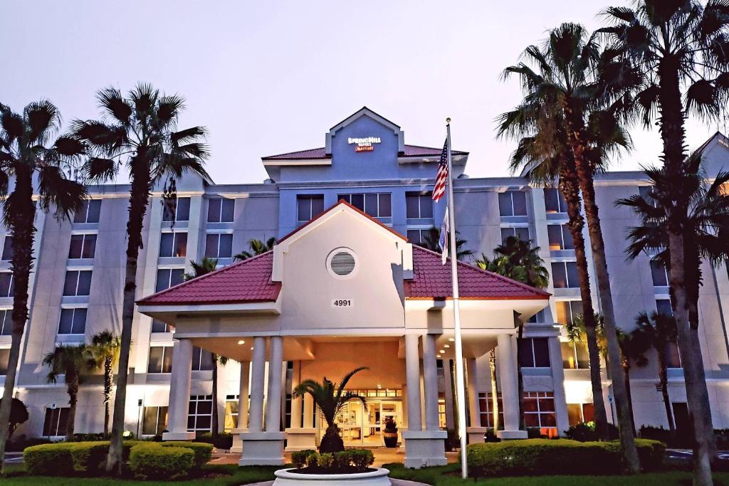 a building with palm trees in front of it at SpringHill Suites by Marriott Orlando Lake Buena Vista South in Kissimmee