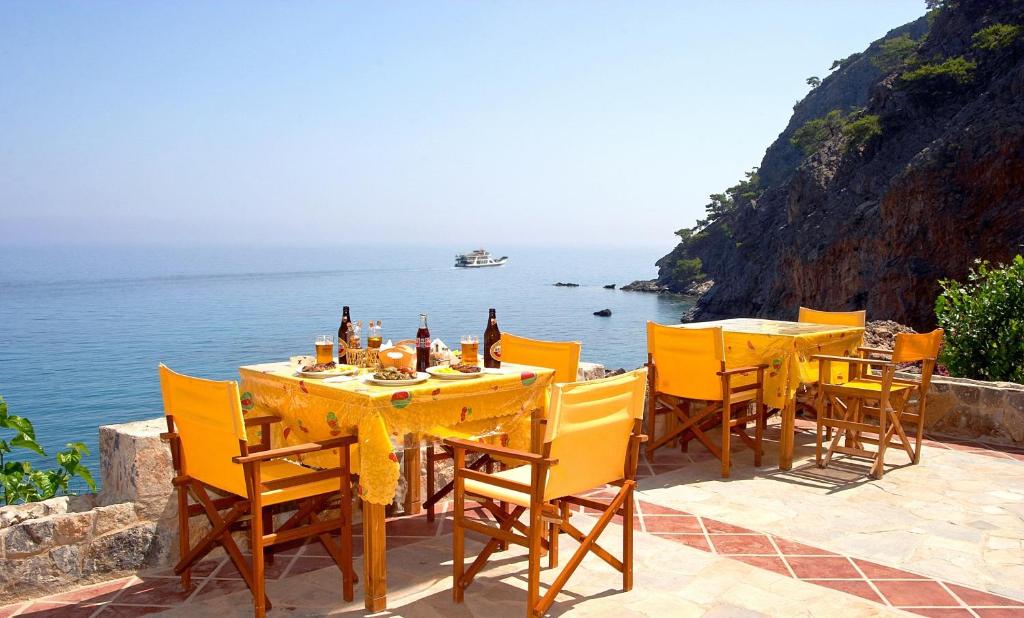 a row of tables with chairs and umbrellas on a beach at Sweet Corner Masxali in Agia Roumeli