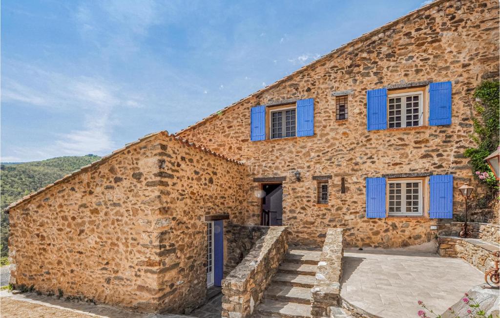 duży kamienny budynek z niebieskimi okiennicami w obiekcie 3 Bedroom Nice Home In Taulis w mieście Taulis