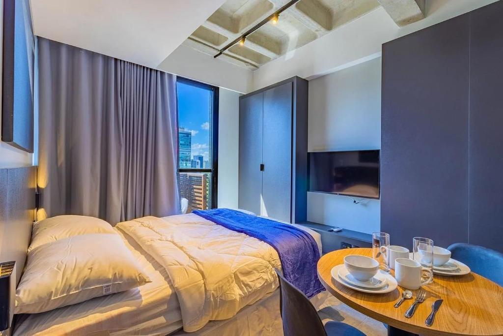 um quarto com uma cama e uma mesa com pratos em TOLIVE One Housi Recife by Carpediem no Recife