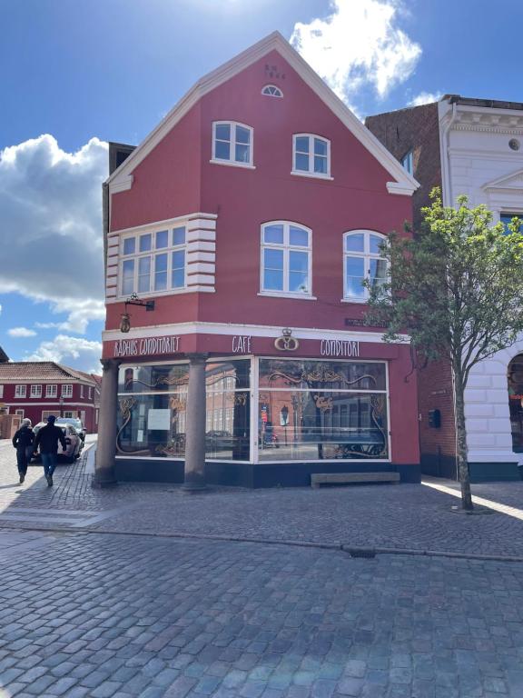 a red building on a street with people walking past it at Cafe Sallys bed and breakfast in Ribe