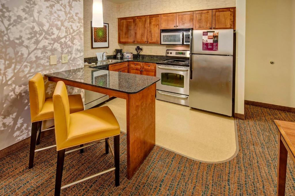 a kitchen with a counter with yellow chairs and a refrigerator at Residence Inn by Marriott Memphis Southaven in Southaven
