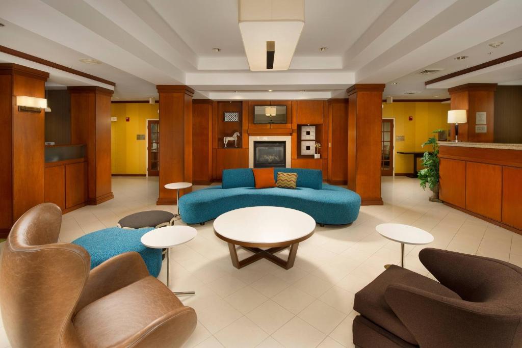 sala de estar con sofá azul, mesas y sillas en Fairfield Inn & Suites by Marriott Marshall en Marshall