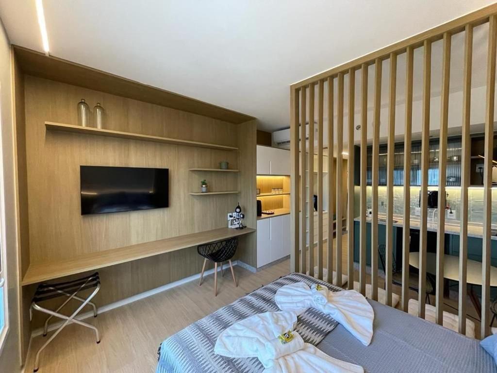 Schlafzimmer mit einem Bett, einem Schreibtisch und einem TV in der Unterkunft Suíte Luxuosa com cozinha Blend Smart 1356 in Goiânia