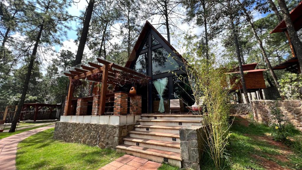 a small building with a staircase in the grass at Chalets Villa Maria in Huasca de Ocampo