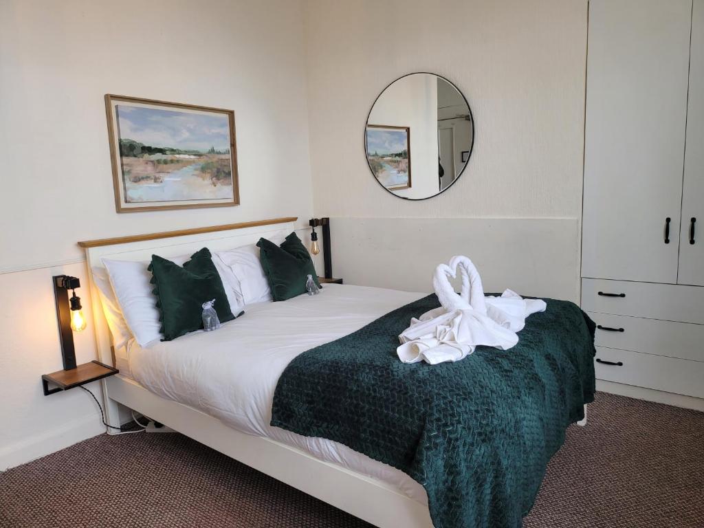 una camera da letto con un letto con una coperta verde e uno specchio di SeaView ground floor flat fast WiFi & FREE PARKING a Scarborough