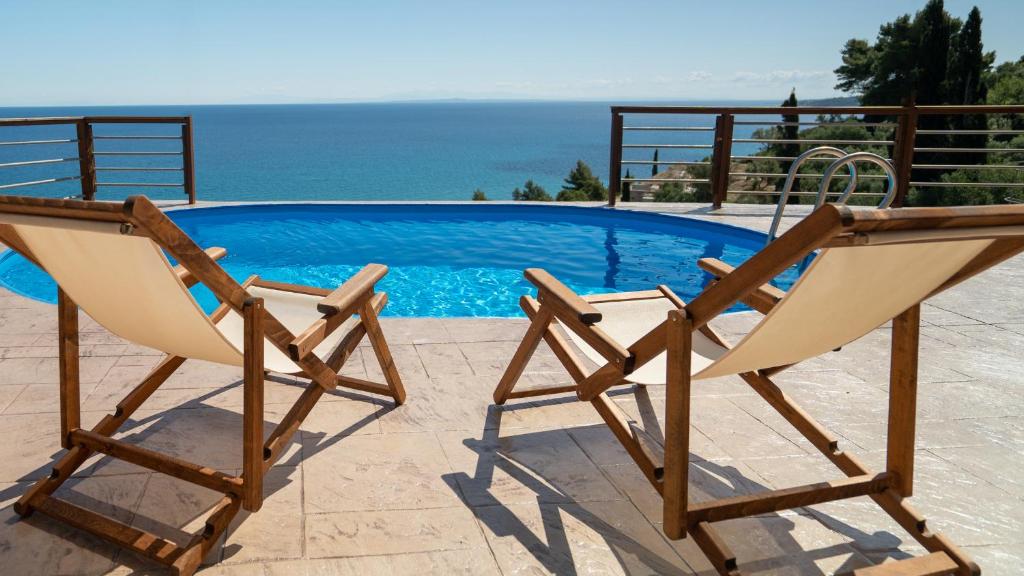 a pair of chairs sitting next to a swimming pool at Zante Xigia Bay villas in Khartáta