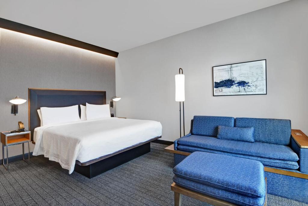 a hotel room with a bed and a blue couch at Courtyard by Marriott Hamilton in Hamilton