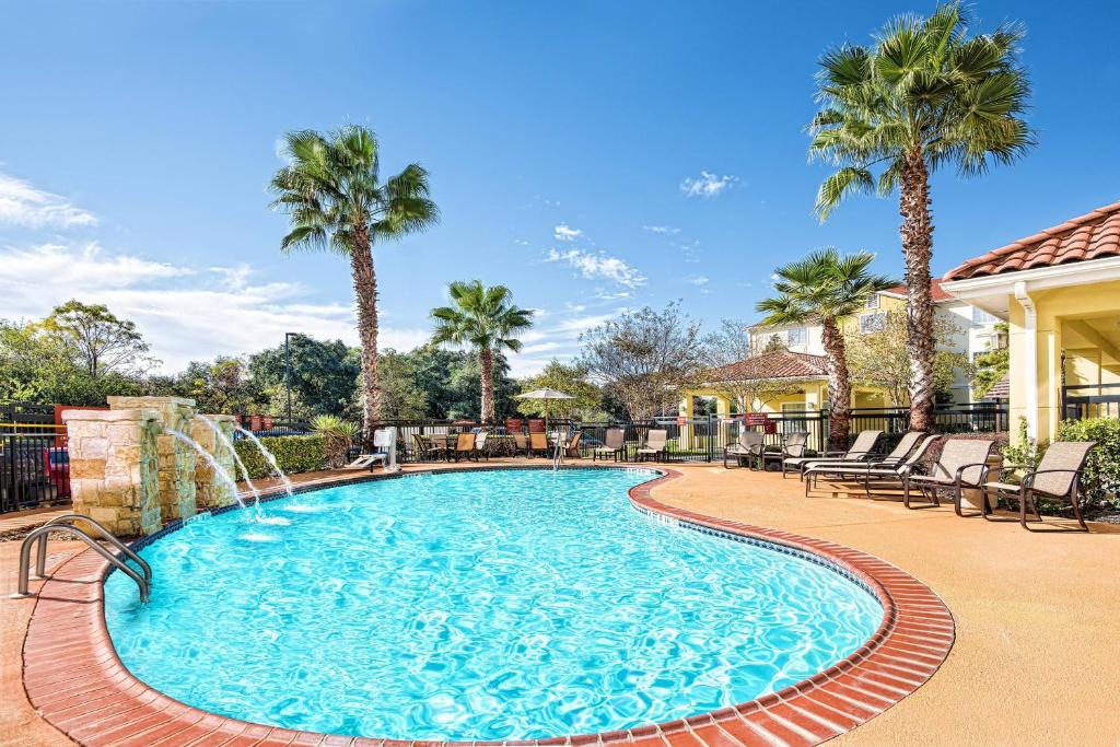 a swimming pool with a waterfall and palm trees at TownePlace Suites by Marriott San Antonio Northwest in San Antonio