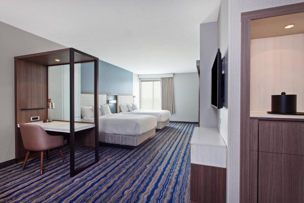 a hotel room with two beds and a desk and a television at SpringHill Suites by Marriott Huntington Beach Orange County in Huntington Beach