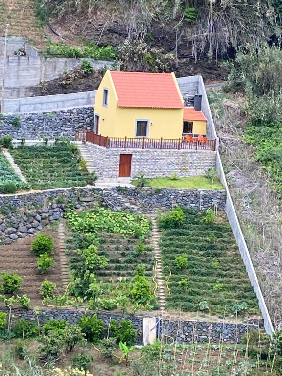 een geel huis met een rood dak op een heuvel bij casa caminho da praia in Porto da Cruz