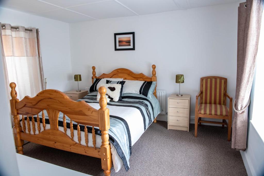 a bedroom with a wooden bed and a chair at Sheila's Cottage Ballyheigue in Ballyheigue