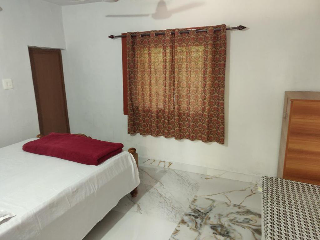 a bedroom with a bed and a window with a curtain at Kaikane homestay in Madikeri