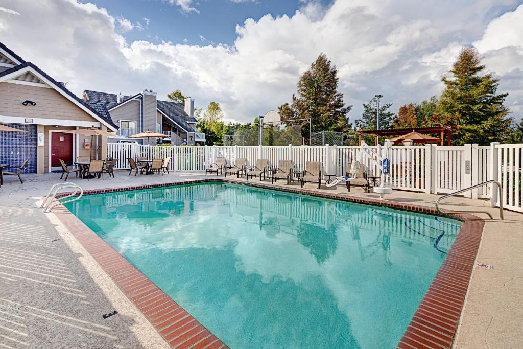 a swimming pool with chairs and a fence at Residence Inn Seattle North/Lynnwood Everett in Lynnwood