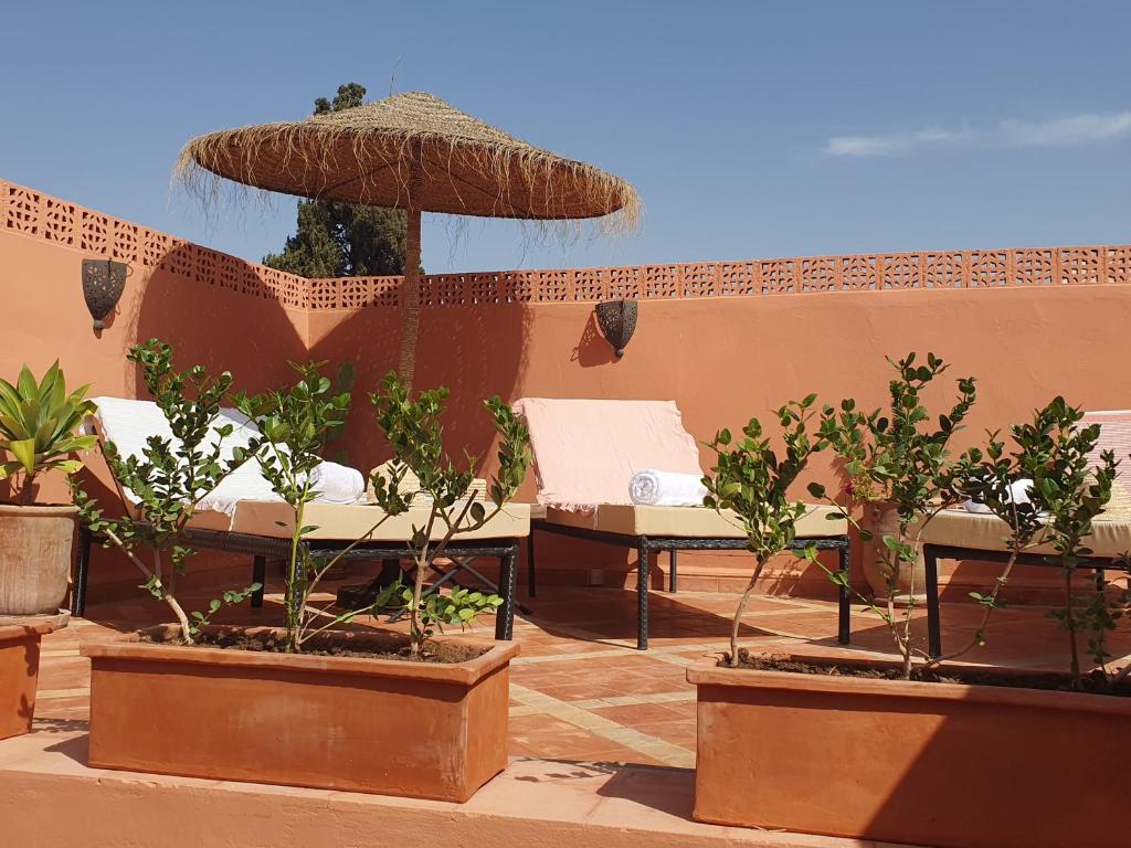 un patio con mesa, sillas y sombrilla en Riad Le Manzil Beldi, en Marrakech