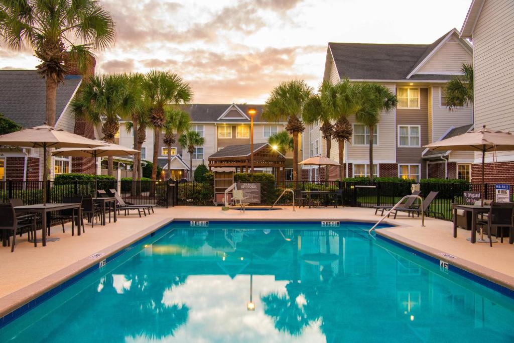 una piscina en un complejo con mesas y sillas en Residence Inn by Marriott Jacksonville Butler Boulevard, en Jacksonville