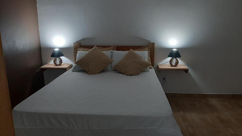 a bedroom with a bed with two lamps on both sides at Rancho Esperança, pouso e comida a lenha in Paraty