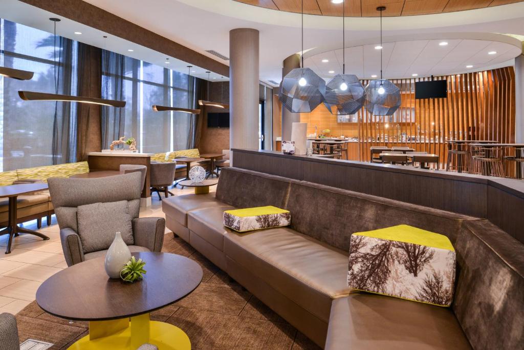 eine Lobby mit einem Sofa und Stühlen sowie ein Restaurant in der Unterkunft SpringHill Suites Irvine John Wayne Airport / Orange County in Irvine