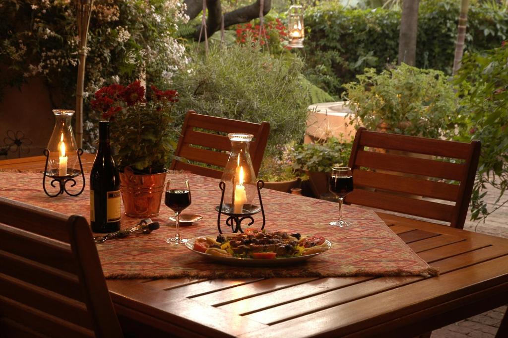 een houten tafel met een bord eten en wijnglazen bij Elonda B&B in Pretoria