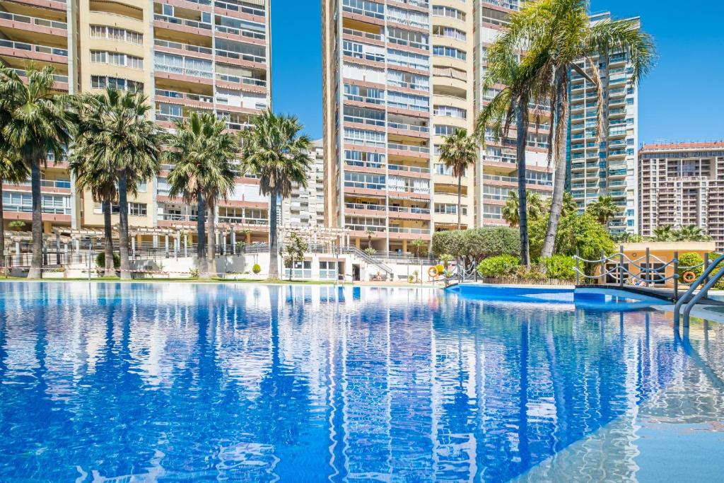 ビリャホヨサにあるCala Palmera 10-C Apartment Playa La Cala Beachのヤシの木と建物のあるスイミングプール