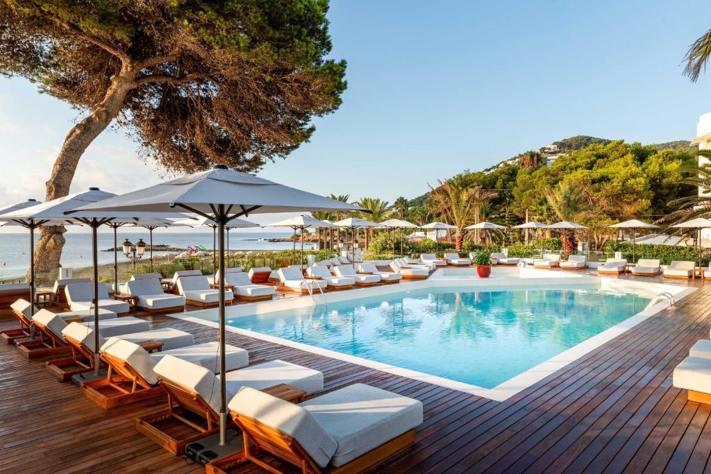 a swimming pool with lounge chairs and umbrellas at Hotel Riomar, Ibiza, a Tribute Portfolio Hotel in Santa Eularia des Riu