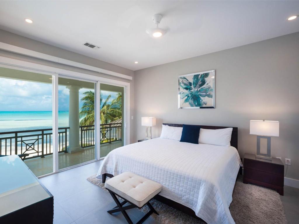 a bedroom with a bed and a view of the ocean at Luxury Cayman Villas in Driftwood Village