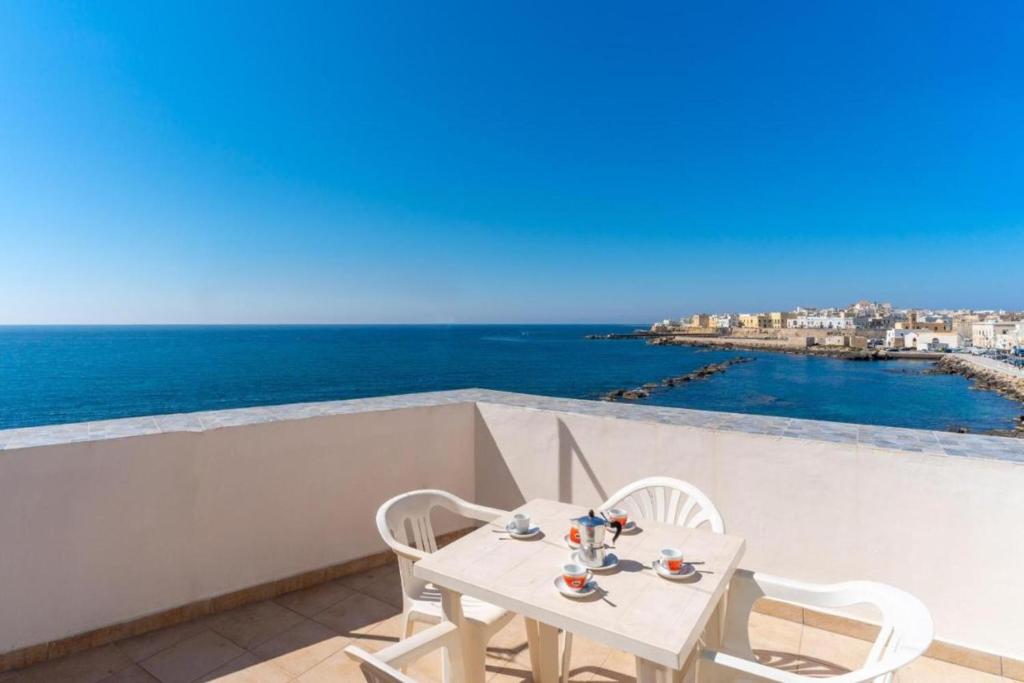 a table and chairs on a balcony with a view of the ocean at ATTICO SUL MARE in Gallipoli