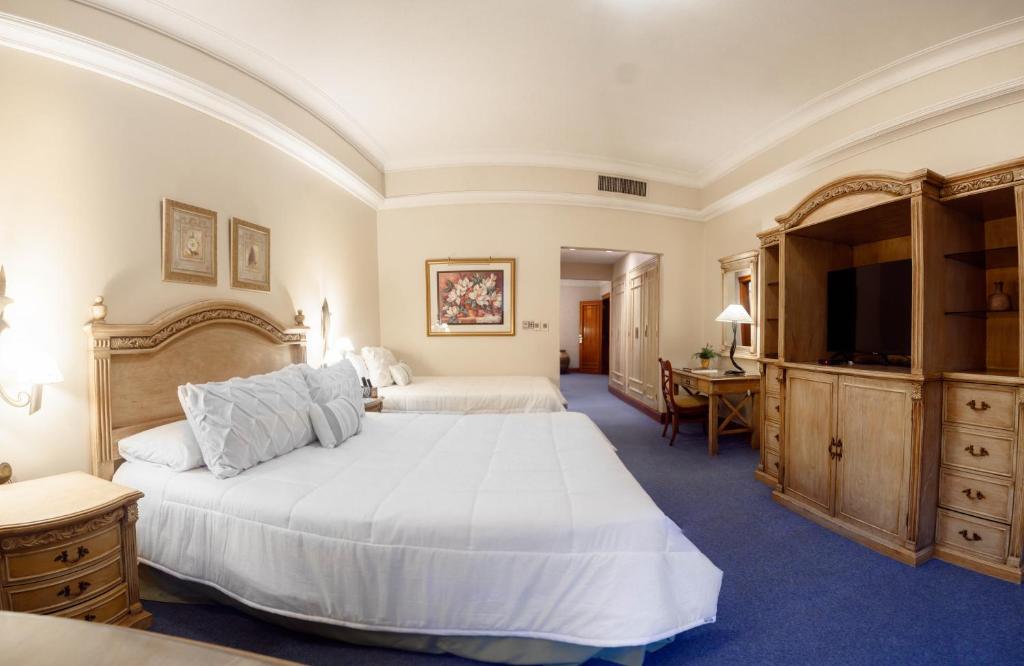 a large bedroom with two beds and a flat screen tv at Granados Park Hotel in Asuncion