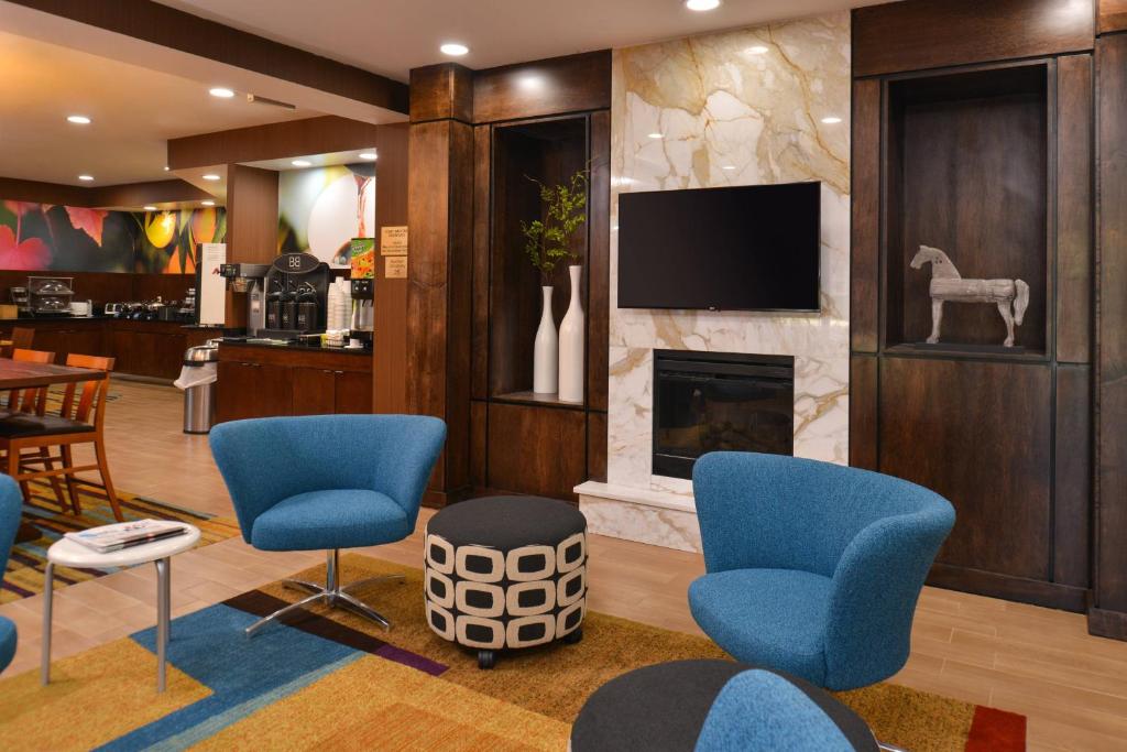 a lobby with blue chairs and a fireplace at Fairfield Inn & Suites Louisville North in Jeffersonville