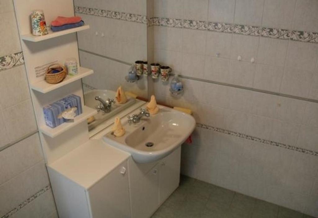 La salle de bains blanche est pourvue d'un lavabo et d'un miroir. dans l'établissement Alpe Monte Massella, à Poschiavo