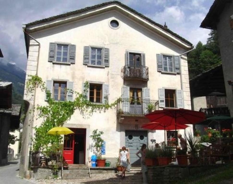 a white house with two people walking in front of it at Ferienwohnung - a85554 in Promontogno