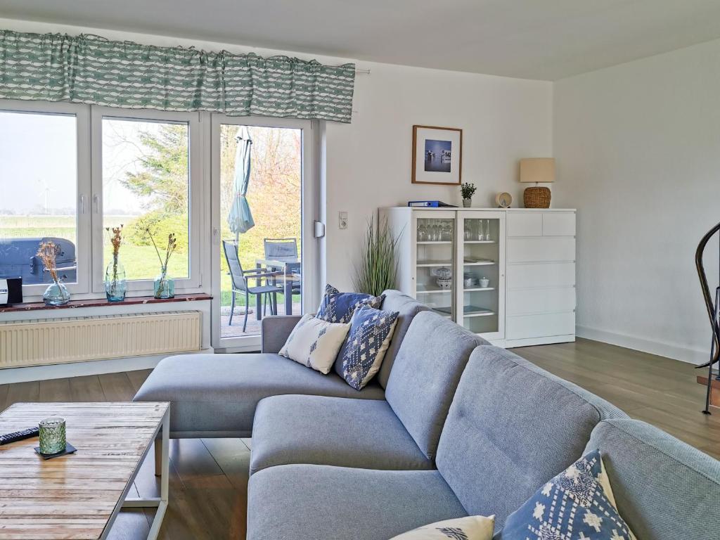 a living room with a blue couch and a table at Traumhafter Nordseeurlaub im modernen Ferienhaus mit großem Garten, Kamin und Strandkorb in Werdum